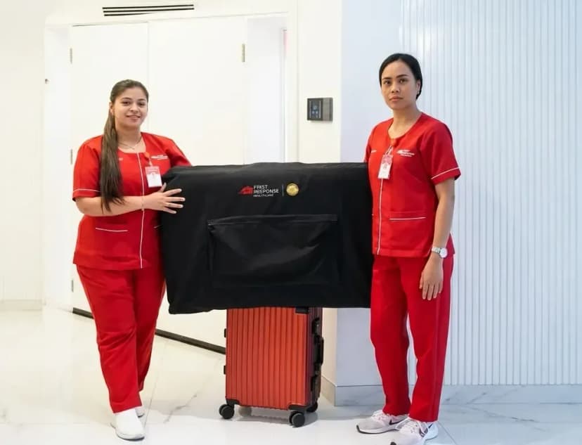Female physiotherapists in red uniforms with mobile treatment equipment for at-home care