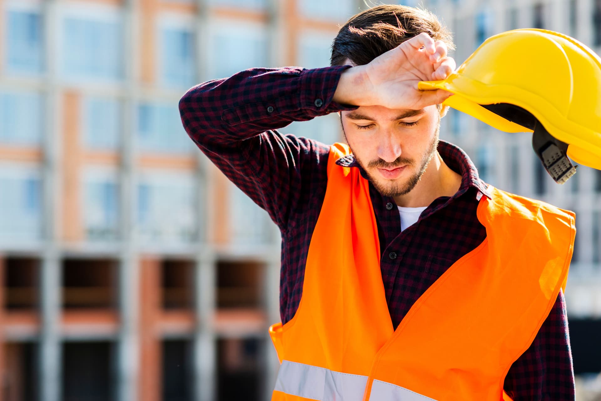 Tired construction worker experiencing heat exhaustion during Dubai summer outdoor work