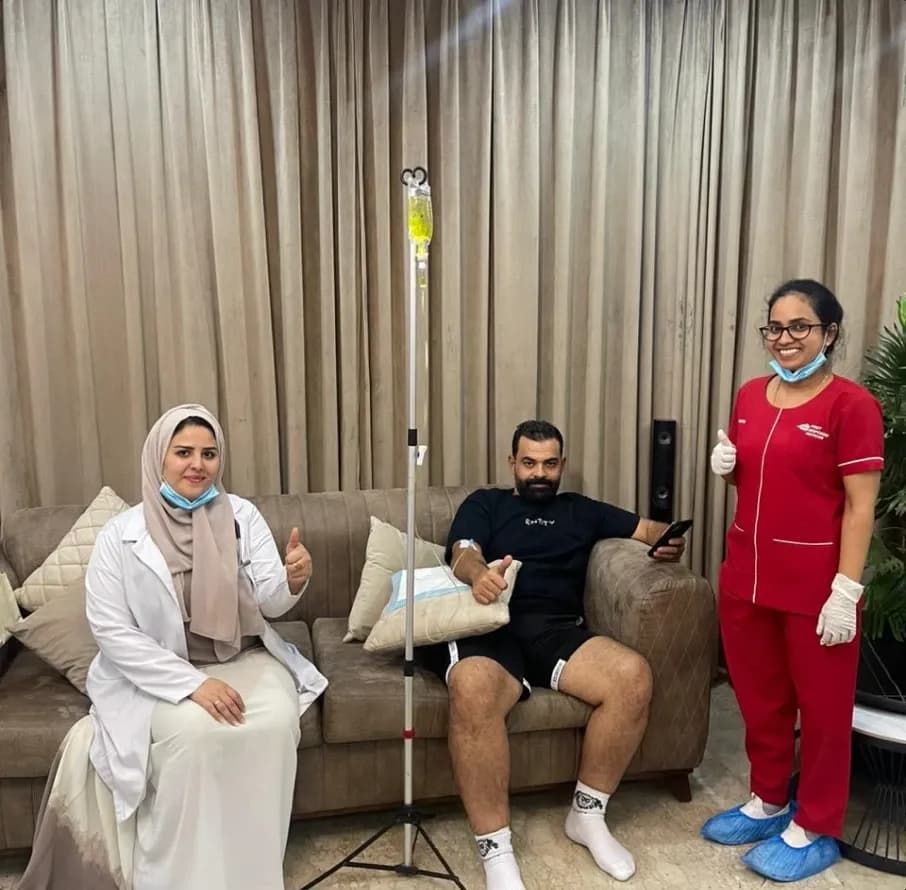 A professional home healthcare nurse preparing a personalized intravenous (IV) drip infusion for a patient relaxing at home.