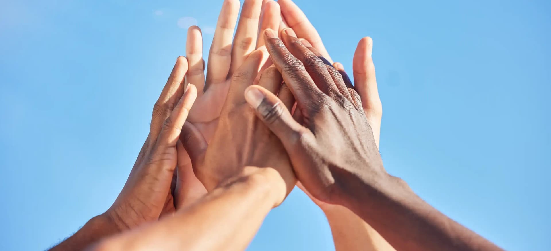 A group of people raising and stacking their hands together, representing First Response Healthcare commitment to accessible care and community trust.
