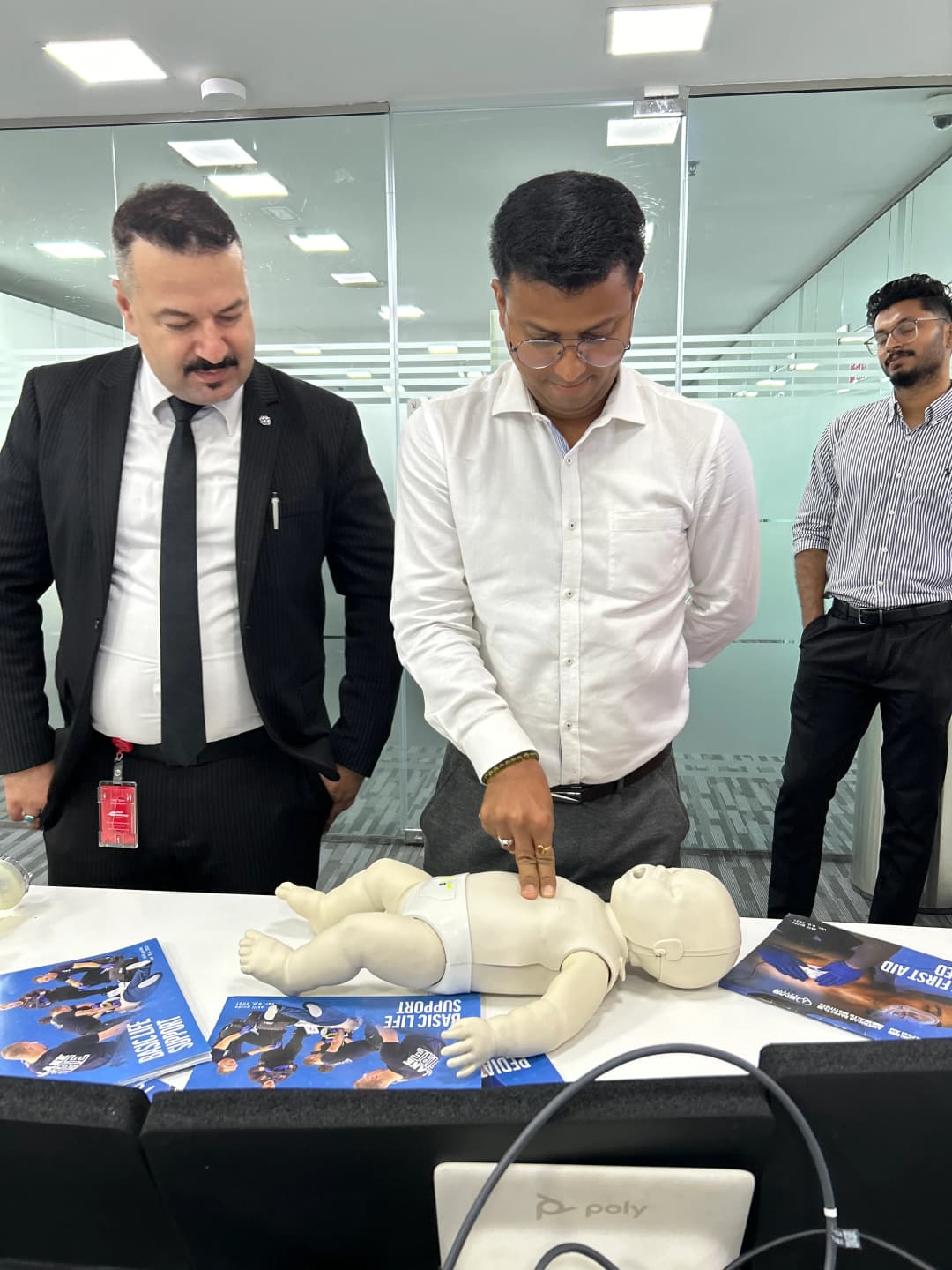 Corporate professionals and medical trainers participating in an interactive first aid training demo inside an office setting.