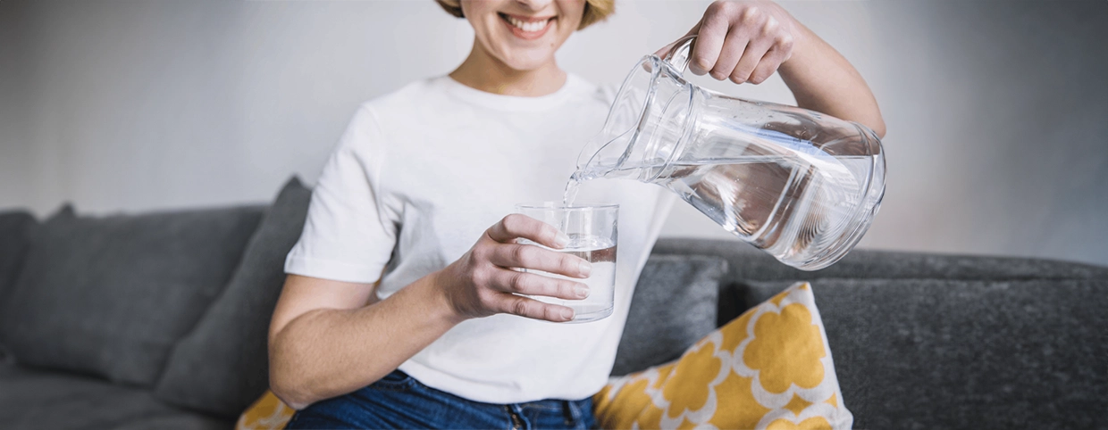 A woman on a couch holds a glass of water