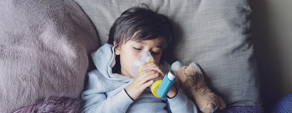 Kid having asthma using a spacer asthma inhaler