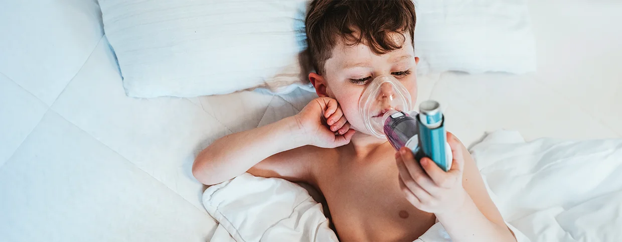 Small child suffering from asthma using spacer asthma inhaler