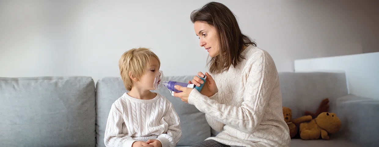 Mother helping her son with using spacer asthma inhaler