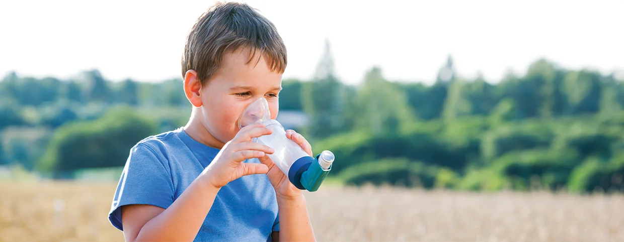 Small child using spacer asthma inhaler