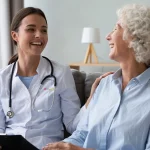 A doctor providing personalized care to a patient while sitting together on the couch at home.