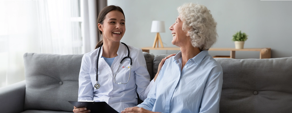 A doctor providing personalized care to a patient while sitting together on the couch at home.