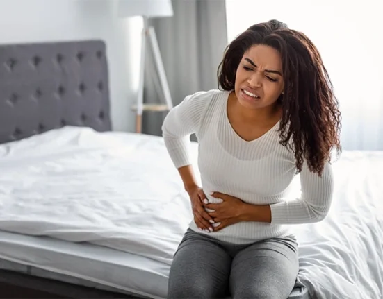 Woman holding her abdomen, indicating right side lower abdominal pain
