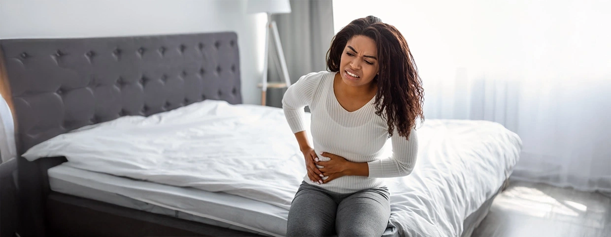 Woman holding her abdomen, indicating right side lower abdominal pain