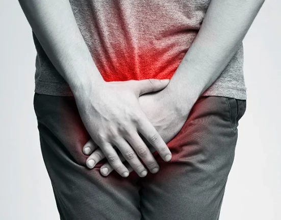 Man holding his lower abdomen due to UTI pain