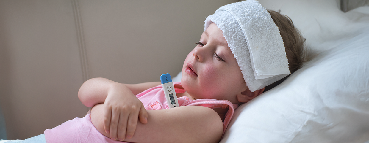 A young child lying in bed with a cold towel on the forehead