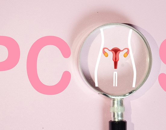 A magnifying glass highlighting a uterus illustration with the word PCOS in the background