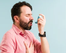 A man having an asthma attack and using an inhaler