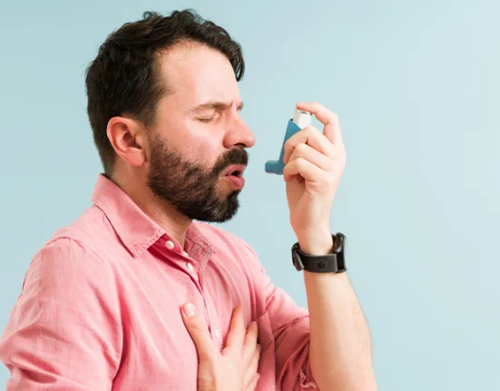 A man having an asthma attack and using an inhaler