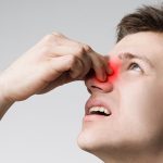 A man holding his nose with a highlighted sinus area indicating chronic sinusitis