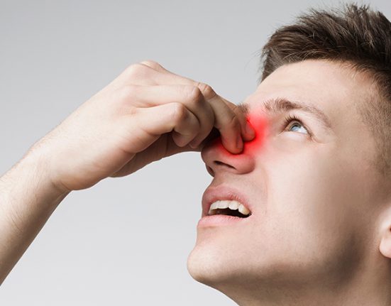 A man holding his nose with a highlighted sinus area indicating chronic sinusitis