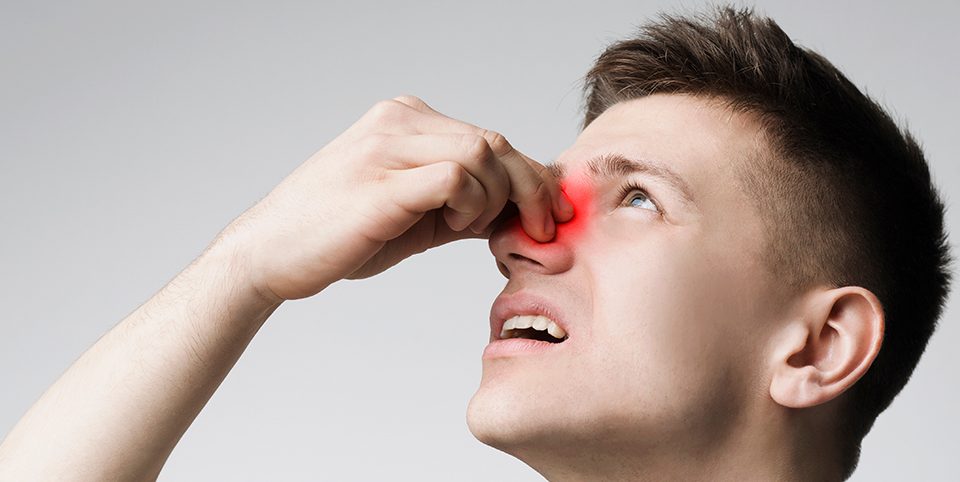 A man holding his nose with a highlighted sinus area indicating chronic sinusitis