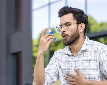 A man using an inhaler for asthma relief outdoors