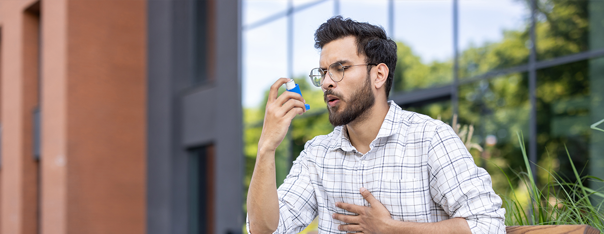 A man using an inhaler for asthma relief outdoors