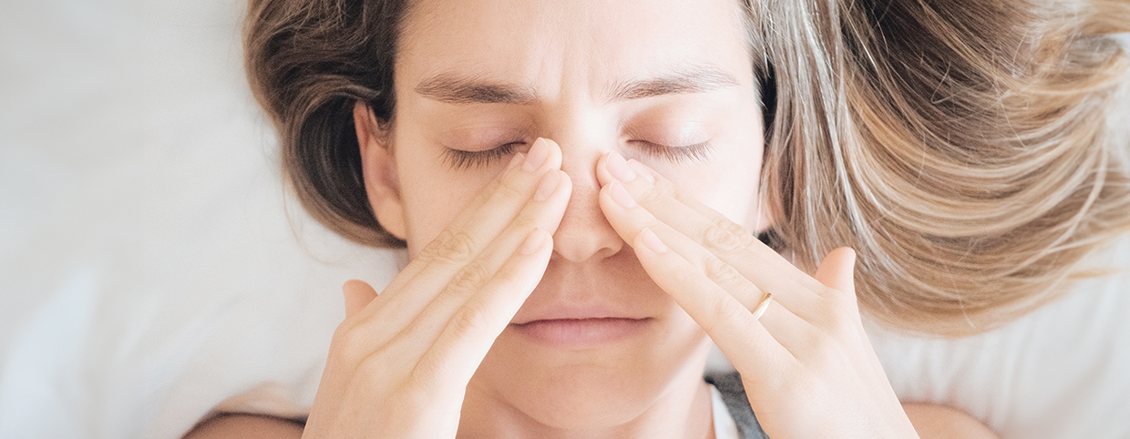 A woman pressing her sinus area due to chronic sinusitis discomfort