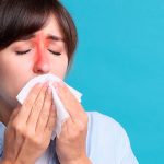 A woman with inflamed sinus areas blowing her nose, indicating chronic sinusitis