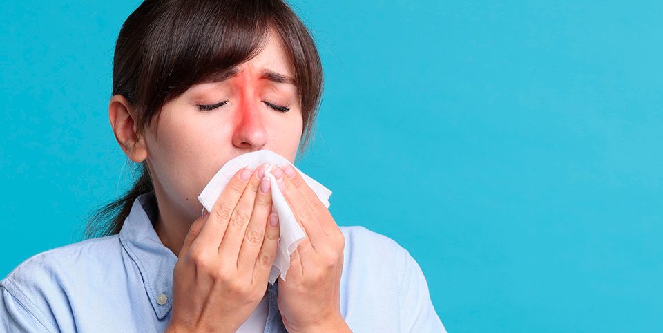 A woman with inflamed sinus areas blowing her nose, indicating chronic sinusitis