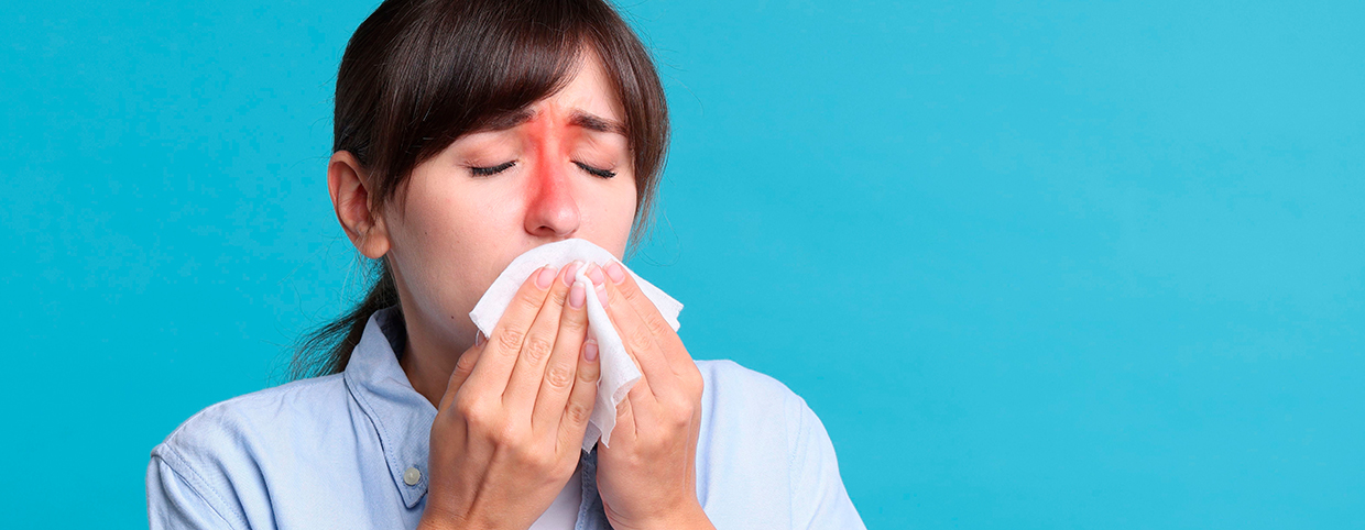 A woman with inflamed sinus areas blowing her nose, indicating chronic sinusitis