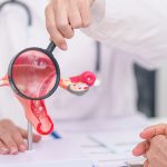 Doctor holding a uterus model with a magnifying glass highlighting PCOS